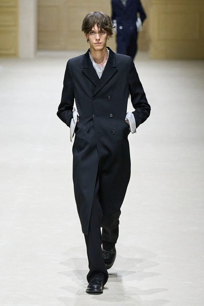 Prada Fall 2026 menswear runway model wearing the black double-breasted coat with exaggerated striped cuffs later worn by Pedro Pascal at AFI FEST.