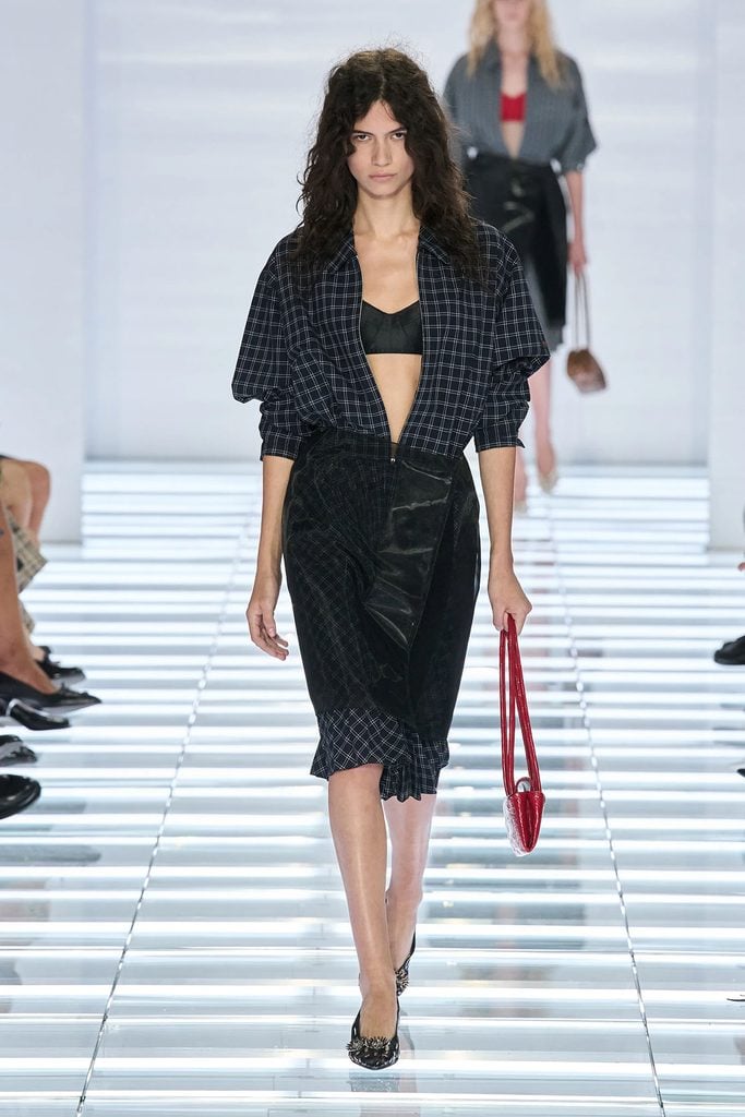 Model wearing a checked dress with a sheer organza skirt overlay on the Prada Spring 2027 runway.