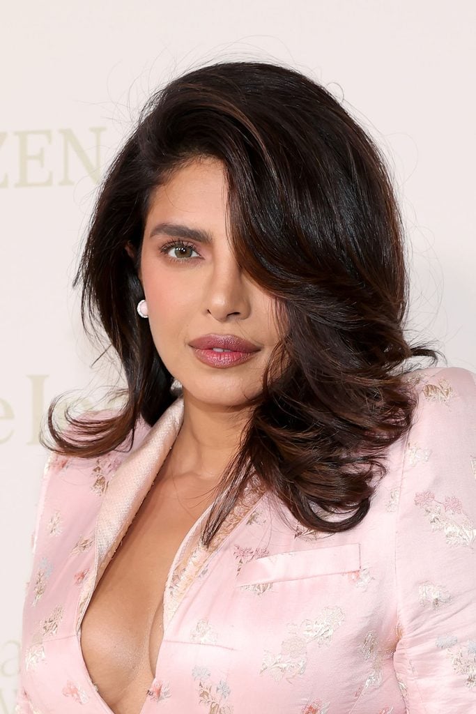 Close-up of Priyanka Chopra's voluminous side-swept hairstyle, pearl earrings and pink floral Matières Fécales jacket at the InStyle Imagemaker Awards.