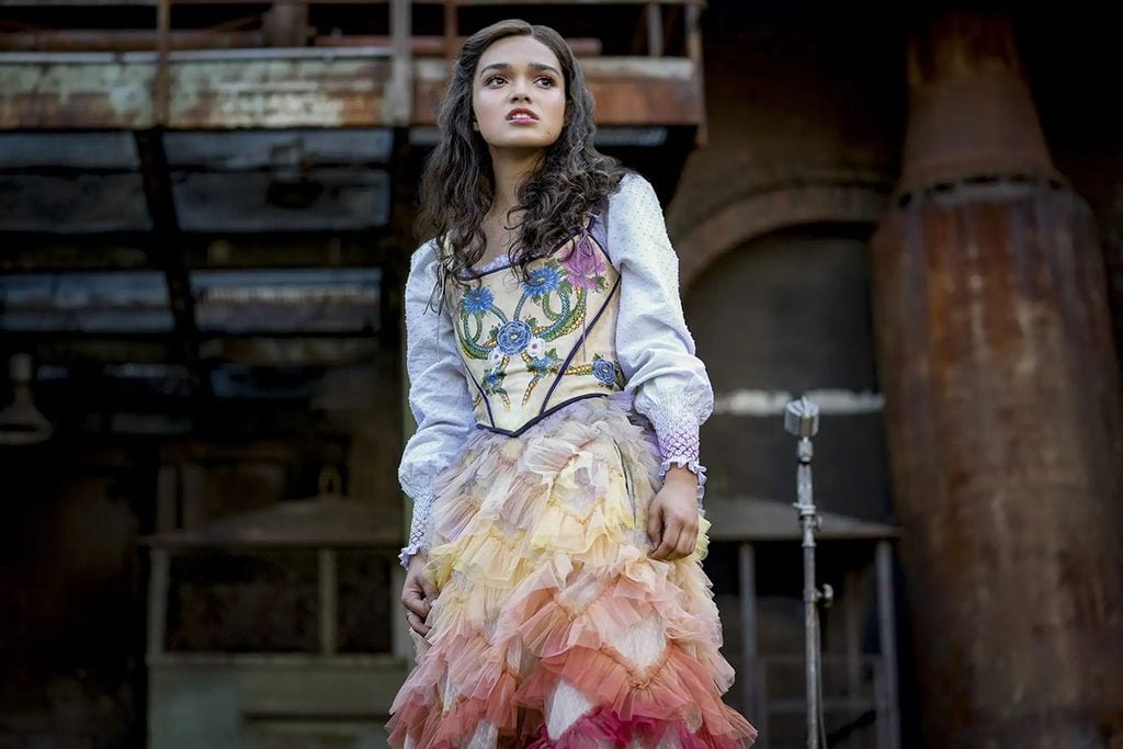 Rachel Zegler as Lucy Gray Baird wearing a floral-embroidered corset dress with white puff sleeves and a tiered pastel ruffle skirt in The Hunger Games: The Ballad of Songbirds & Snakes.