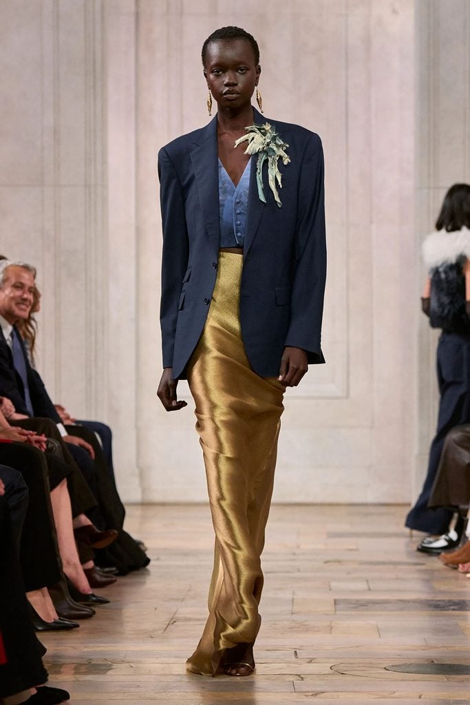 Model wearing a navy blazer, blue waistcoat and gold satin skirt on the Ralph Lauren Spring 2027 runway.