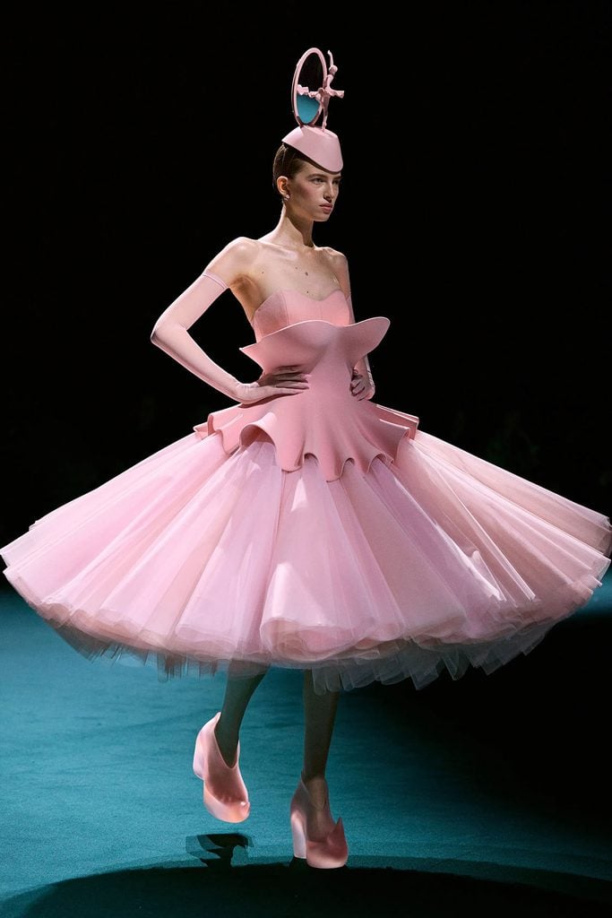 Robert Wun Fall 2026 Couture runway model wears the pink sculptural peplum dress with a voluminous tulle skirt, matching gloves, ballerina headpiece and sculptural heels, later worn by Elle Fanning at The Hunger Games London premiere.