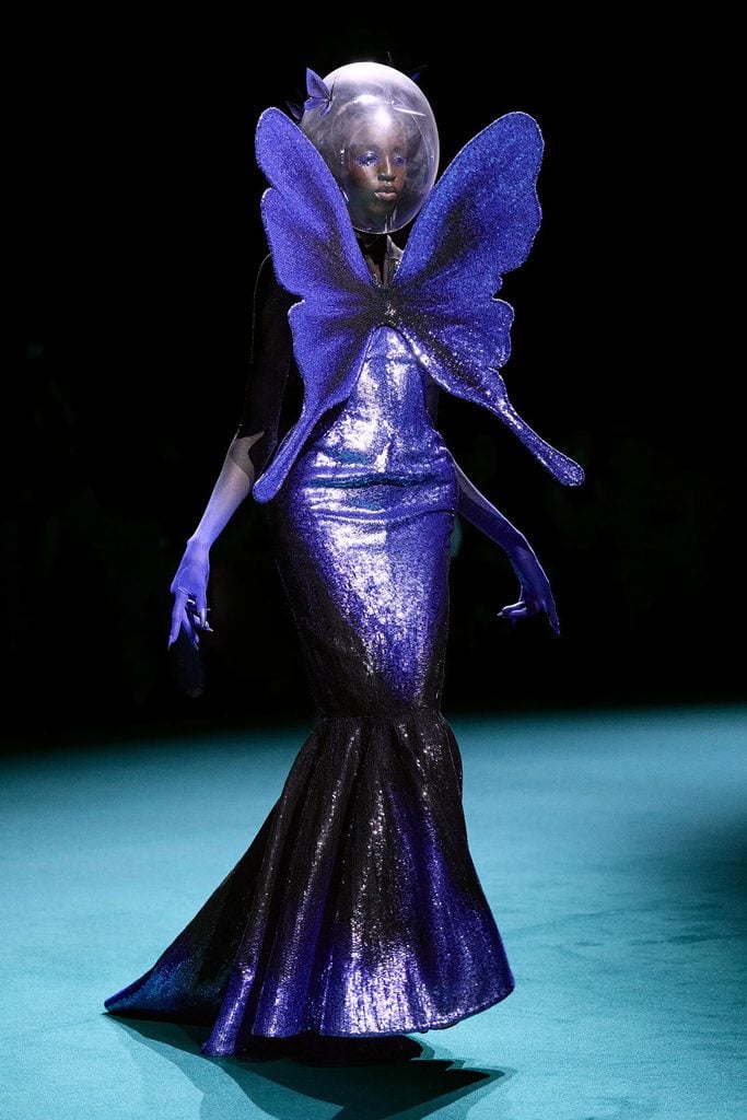 Robert Wun Fall 2026 Couture runway model in a purple butterfly gown with a transparent spherical headpiece and sculptural wings