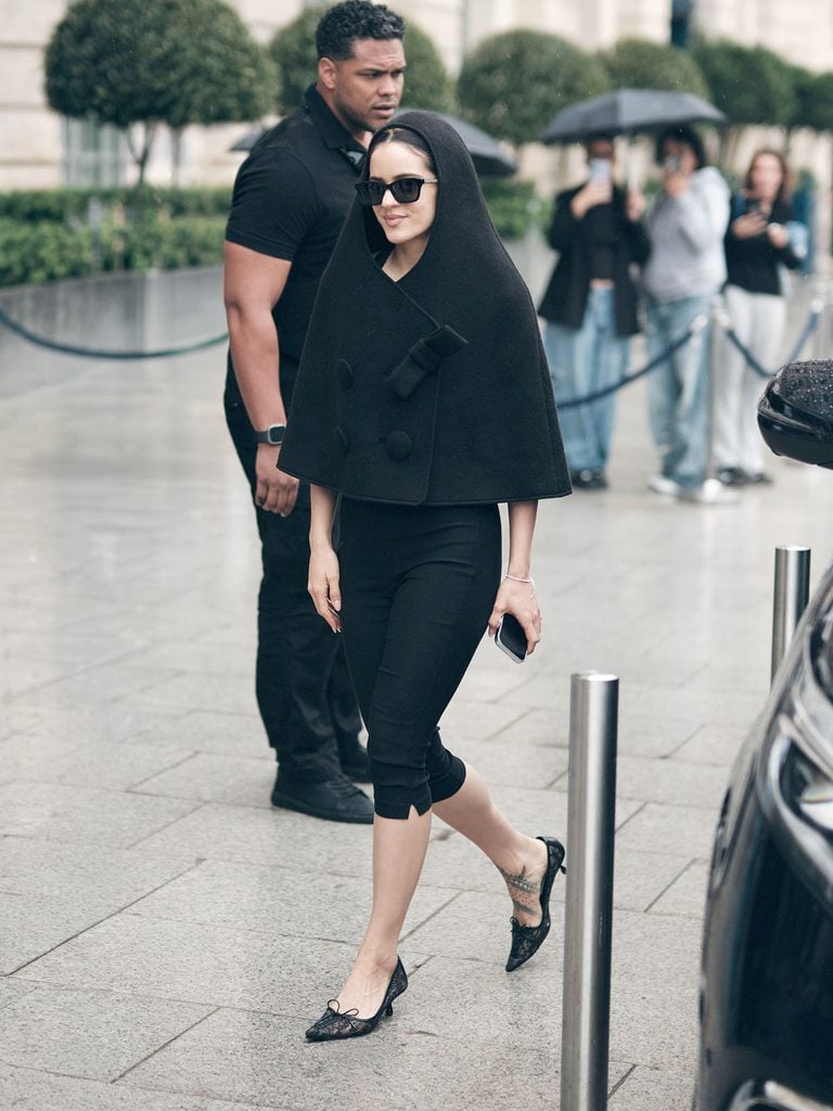 Rosalía wearing a Vaquera Fall 2026 hooded cape with black capri trousers during Paris Fashion Week.