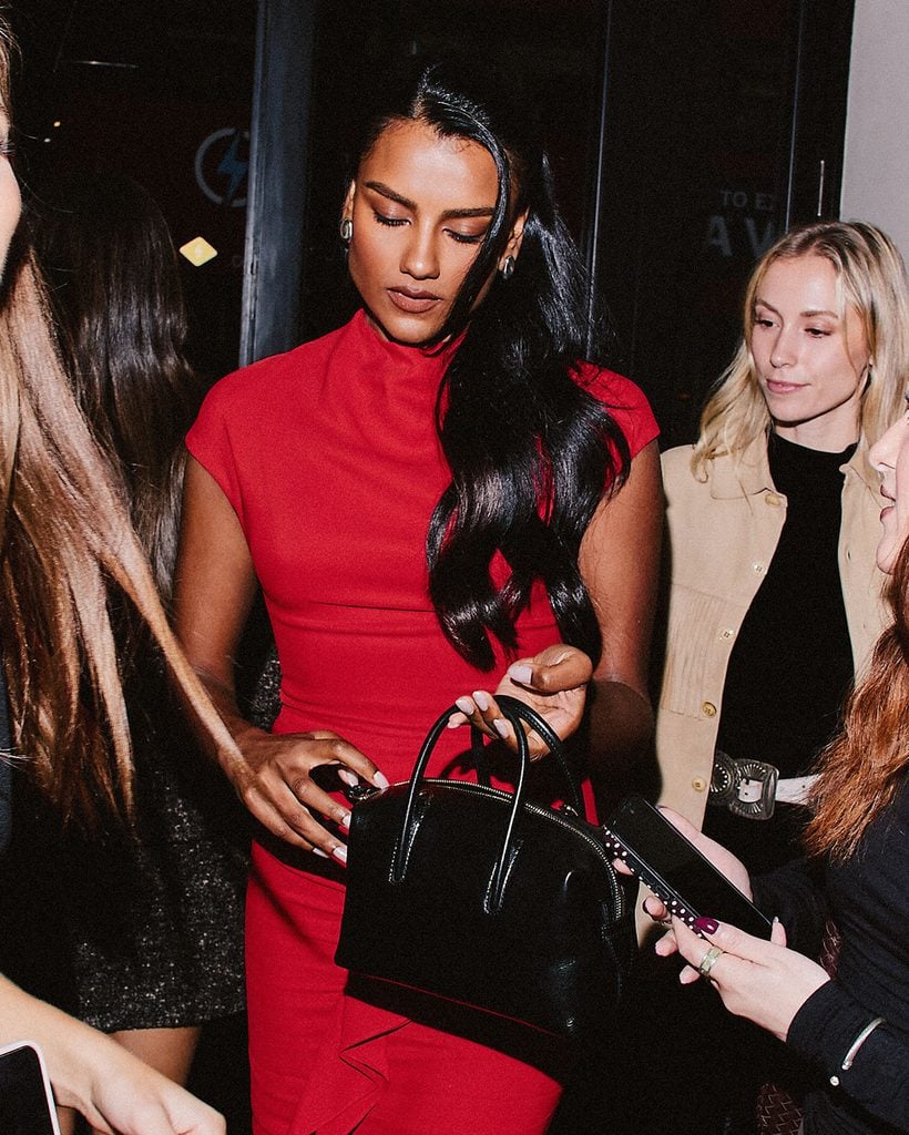 Simone Ashley carries a black DeMellier handbag while meeting guests at the label's first London flagship store celebration.
