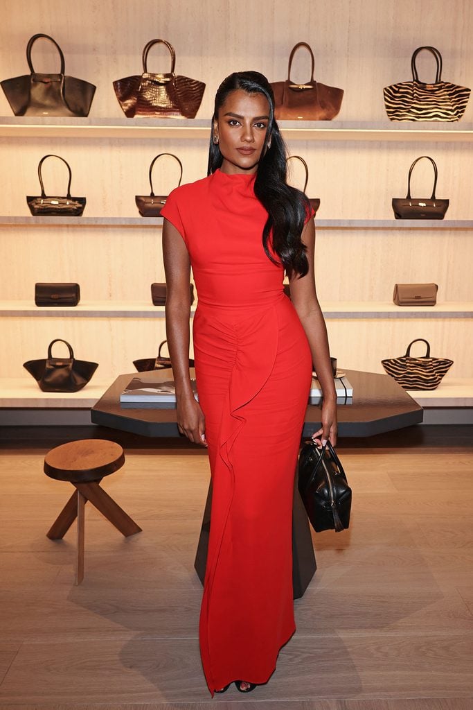 Simone Ashley attends the DeMellier London flagship store opening wearing a red Tove Beth dress styled with a black Stockholm handbag and black mules.