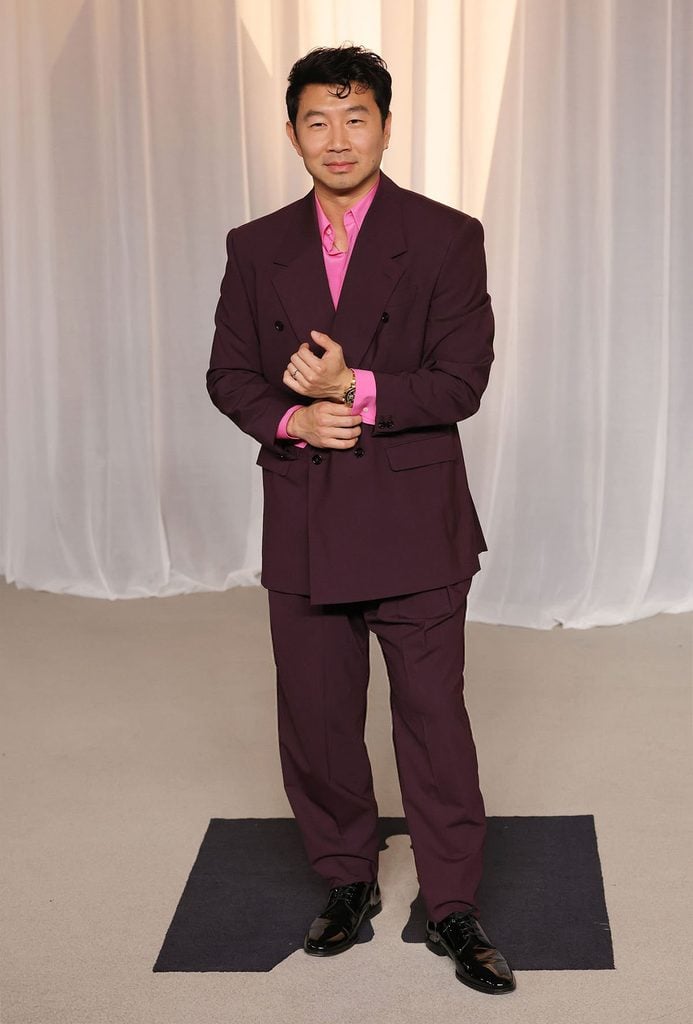 Simu Liu wearing a burgundy Dolce & Gabbana double-breasted suit with a pink shirt at the 2026 Academy Museum Gala