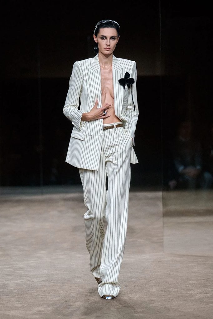 Tom Ford Spring 2027 runway model wearing the white pinstripe suit with black floral embellishment later worn by Louisa Jacobson at the WWD Honors.