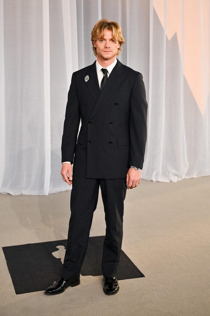 Tom Rhys Harries in a Burberry double-breasted suit with a decorative brooch at the Academy Museum Gala in Los Angeles.