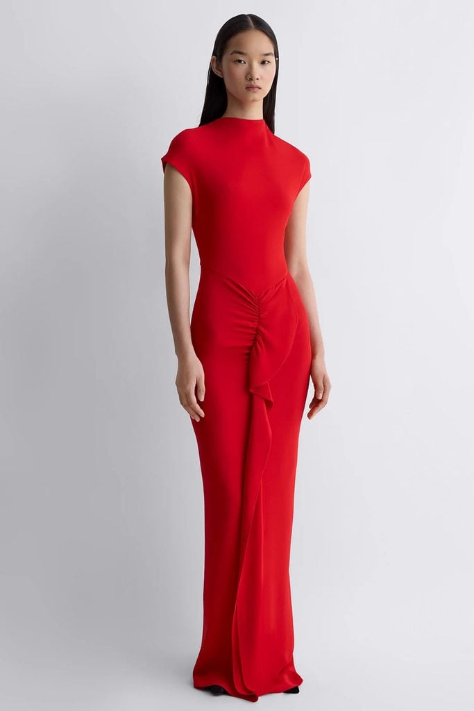 Tove Beth dress in red, featuring a high neckline, cap sleeves and gathered draping down the front, shown on the brand's model.