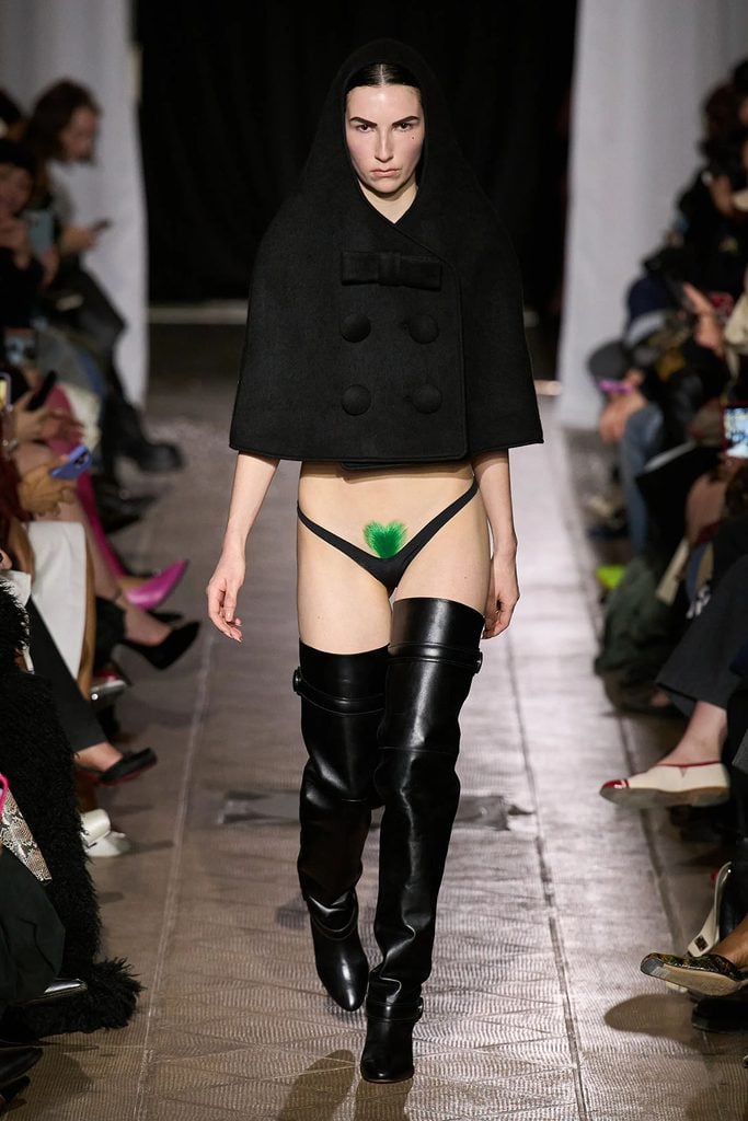Vaquera Fall 2026 hooded black cape styled with briefs and thigh-high boots on the runway.