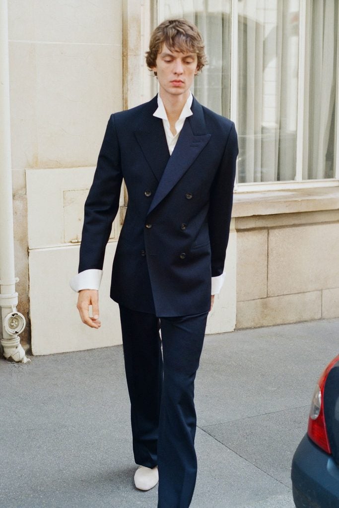 Model wearing a navy Wales Bonner Spring 2027 double-breasted suit with wide lapels and an open-collar white shirt, referenced by Bukayo Saka at the 2026 Ballon d'Or Awards.