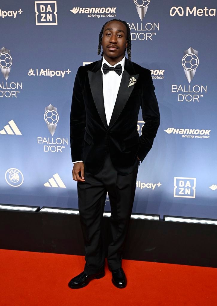 Yan Diomandé wearing a black Dolce & Gabbana tuxedo with a brooch and loose-fitting trousers at the 2026 Ballon d'Or Awards.
