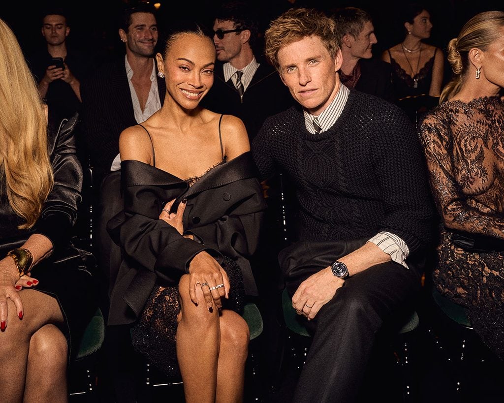 Zoƫ SaldaƱa in a black Saint Laurent jacket alongside Eddie Redmayne at the Spring 2027 show in Paris.