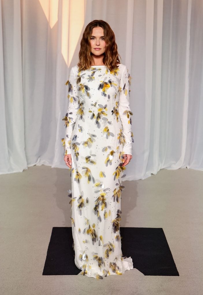 Zoey Deutch in a white Prada gown with yellow and grey floral sequin embellishments at the 2026 Academy Museum Gala
